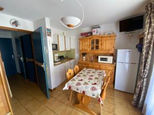 a kitchen with a table and a white refrigerator at Appartement d'une chambre avec balcon a Praz sur Arly in Praz-sur-Arly