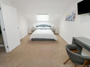 a white bedroom with a bed and a chair at Springwell Lodge in Exeter