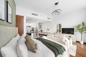 a bedroom with a white bed and a living room at Silkhaus Chic Luxury Studio Opposite Silicon Oasis Shopping Mall in Dubai