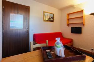 a room with a desk with a red couch and a table at Plein Sud - 2301 - Studio pied des pistes - 2 pers in Les Deux Alpes