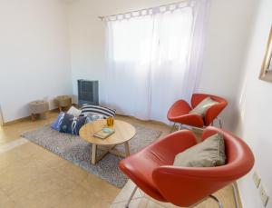 Una sala de estar con dos sillas rojas y una mesa. en Linea Recta Sur- Huemul, departamento amplio, de 3 dormitorios a pasos del mar, en Puerto Madryn
