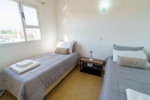 2 camas en una habitación con 2 ventanas en Huemul, cálido y espacioso, aroma de mar en Puerto Madryn