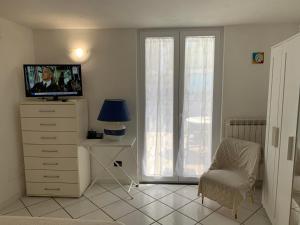 un soggiorno con TV, cassettiera e sedia di Casetta nel Giardino -Ischia a Ischia