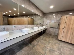 een openbare badkamer met drie wastafels en kasten bij Camping Resort Els Pins in Malgrat de Mar