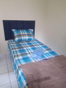 ein Bett mit einer blauen karierten Decke und einem Kissen in der Unterkunft Cantinho Andorinhas in Campinas