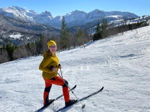 a woman on skis standing on a snow covered slope at Bakkebo Trollstigen in Åndalsnes