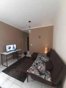 ein Wohnzimmer mit einem Sofa und einem Schreibtisch mit einem Computer in der Unterkunft Cantinho Andorinhas in Campinas