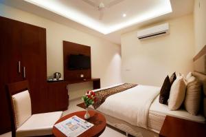 um quarto de hotel com uma cama e uma mesa e uma televisão em Prime Z Suites Hotel- Near Delhi International Airport em Nova Deli