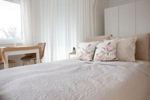 Una cama blanca con almohadas y un escritorio en un dormitorio. en AleApartament en Poznan