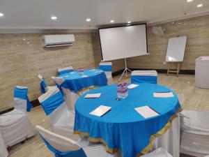 Prime Z Suites Hotel- Near Delhi International Airport في نيودلهي: قاعة اجتماعات ذات طاولات وكراسي زرقاء وشاشة