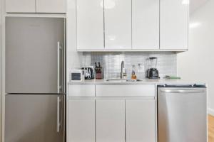 a kitchen with white cabinets and a stainless steel refrigerator at Flat In The Bush in Brooklyn