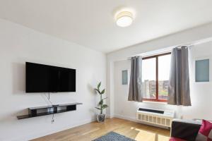 a white living room with a flat screen tv on a wall at Flat In The Bush in Brooklyn