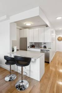 a white kitchen with a counter and two bar stools at Flat In The Bush in Brooklyn