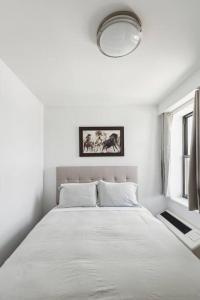 a white bedroom with a large white bed with a window at Flat In The Bush in Brooklyn