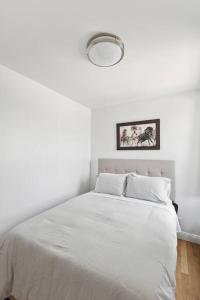a white bedroom with a white bed with a light at Flat In The Bush in Brooklyn