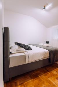 łóżko w pokoju z białą ścianą w obiekcie Apartment Sara w Zagrzebiu