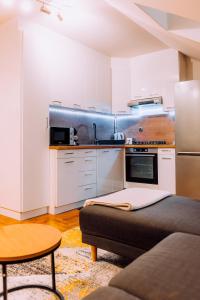 a kitchen with white cabinets and a couch in a room at Apartment Sara in Zagreb