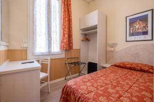 Cette chambre comprend un lit, un bureau et une fenêtre. dans l'établissement Hotel Corso, à Sanremo