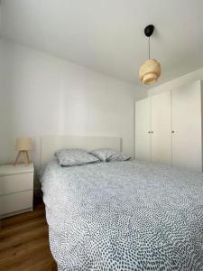 a white bedroom with a bed and a night stand at .L'Armor. Appartement avec terrasse & parking in Les Sables-d'Olonne