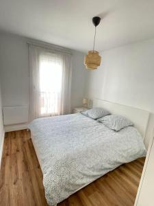 a white bedroom with a bed and a window at .L'Armor. Appartement avec terrasse & parking in Les Sables-d'Olonne