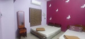 Zimmer mit 2 Betten und einer lila Wand in der Unterkunft PR Residency in Tiruvidaimarudūr