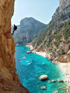 Eine Person, die von einer Klippe in einen Wasserkörper springt. in der Unterkunft bedandclimbing in Baunei