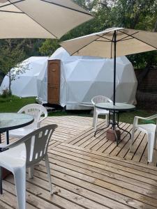 una terraza de madera con mesas, sillas y sombrilla en Refugio Atreyu en Santiago