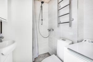 uma casa de banho branca com um chuveiro e um WC. em Centrum - Lovely furnished Studio em Helsínquia