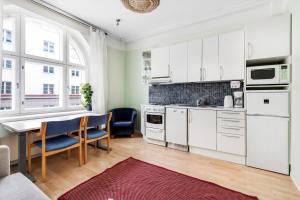 Centrum - Lovely furnished Studio في هلسنكي: مطبخ مع دواليب بيضاء وطاولة وكراسي