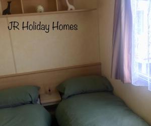 two beds in a room with a yr holiday homes sign on the wall at J.R. Holiday Homes in Saint Osyth