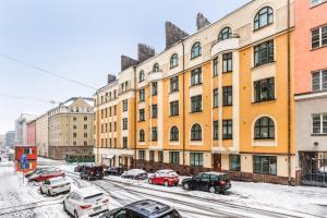 a snowy street with cars parked in front of buildings at Centrum - Lovely furnished Studio in Helsinki