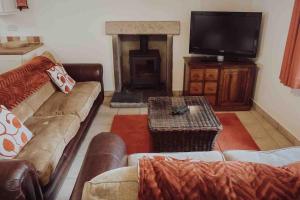 a living room with a couch and a tv at Mabels Cottage, Longnor in Longnor