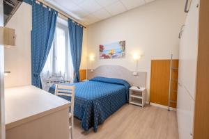 een slaapkamer met een blauw bed in een kamer bij Hotel Corso in Sanremo