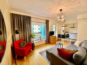 uma sala de estar com um sofá e uma cadeira vermelha em Cozy Residence Apartment - Tallinn City Center em Talin