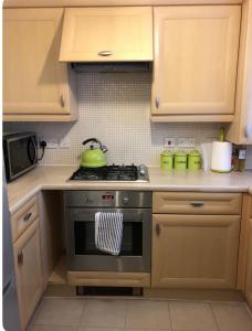 a kitchen with a stove with a green tea kettle at Airport house , Speke in Speke