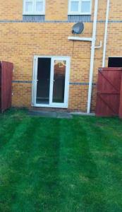 a yard with green grass and a building with a window at Airport house , Speke in Speke