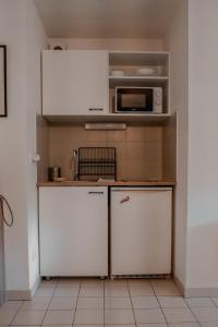 a small kitchen with white cabinets and a microwave at St-OrensBnB - Cosi - WIFI - Parking - Terrasse in Saint-Orens-de-Gameville