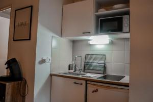 a small kitchen with a sink and a microwave at St-OrensBnB - Cosi - WIFI - Parking - Terrasse in Saint-Orens-de-Gameville