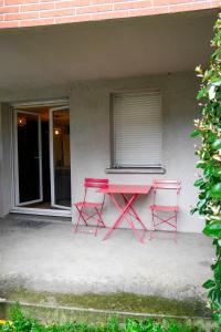 een roze tafel en twee stoelen voor een gebouw bij St-OrensBnB - Cosi - WIFI - Parking - Terrasse in Saint-Orens-de-Gameville