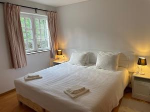 1 dormitorio con 1 cama blanca y 2 toallas en Casa do Olival en Tarouca
