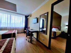 a hotel room with two beds and a desk and a mirror at Hotel El Araucano in Concepción