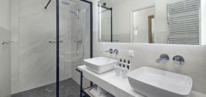 a white bathroom with a sink and a shower at Hotel New York by WestCord in Rotterdam