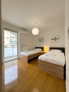 2 camas en una habitación con ventana grande en Gtrip Nea Smyrni Floor Apartment 4F, en Atenas