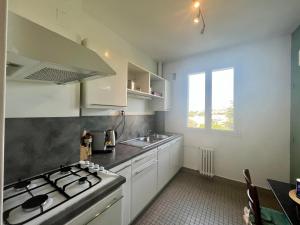 una cocina con estufa horno superior al lado de un fregadero en Le Soleil Levant - Beau T3 moderne et lumineux, en Poitiers