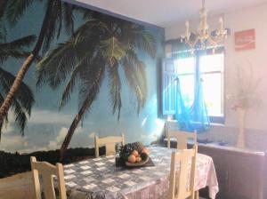 une salle à manger avec une table et une fresque murale de palmiers dans l'établissement Casita bonita de pescador parking y sabanas en opción, à Almería