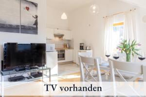 a living room with a tv and a table with chairs at Relax-Apartment mit Balkon, Küche und Parkplatz in Grünenbach