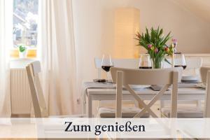 a dining table with two glasses of wine and flowers at Relax-Apartment mit Balkon, Küche und Parkplatz in Grünenbach
