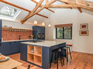 an open kitchen with a blue island with bar stools at 3 Caddaford Barns in Buckfastleigh