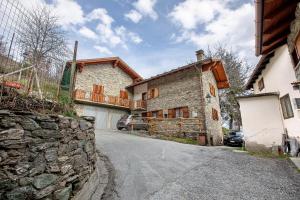a stone house with a stone wall next to a street at Casa Vacanza Menfrey in Verrayes