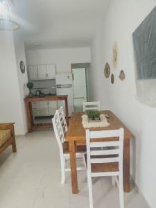 a dining room with a wooden table and white chairs at Departamentos FAVE in Esperanza